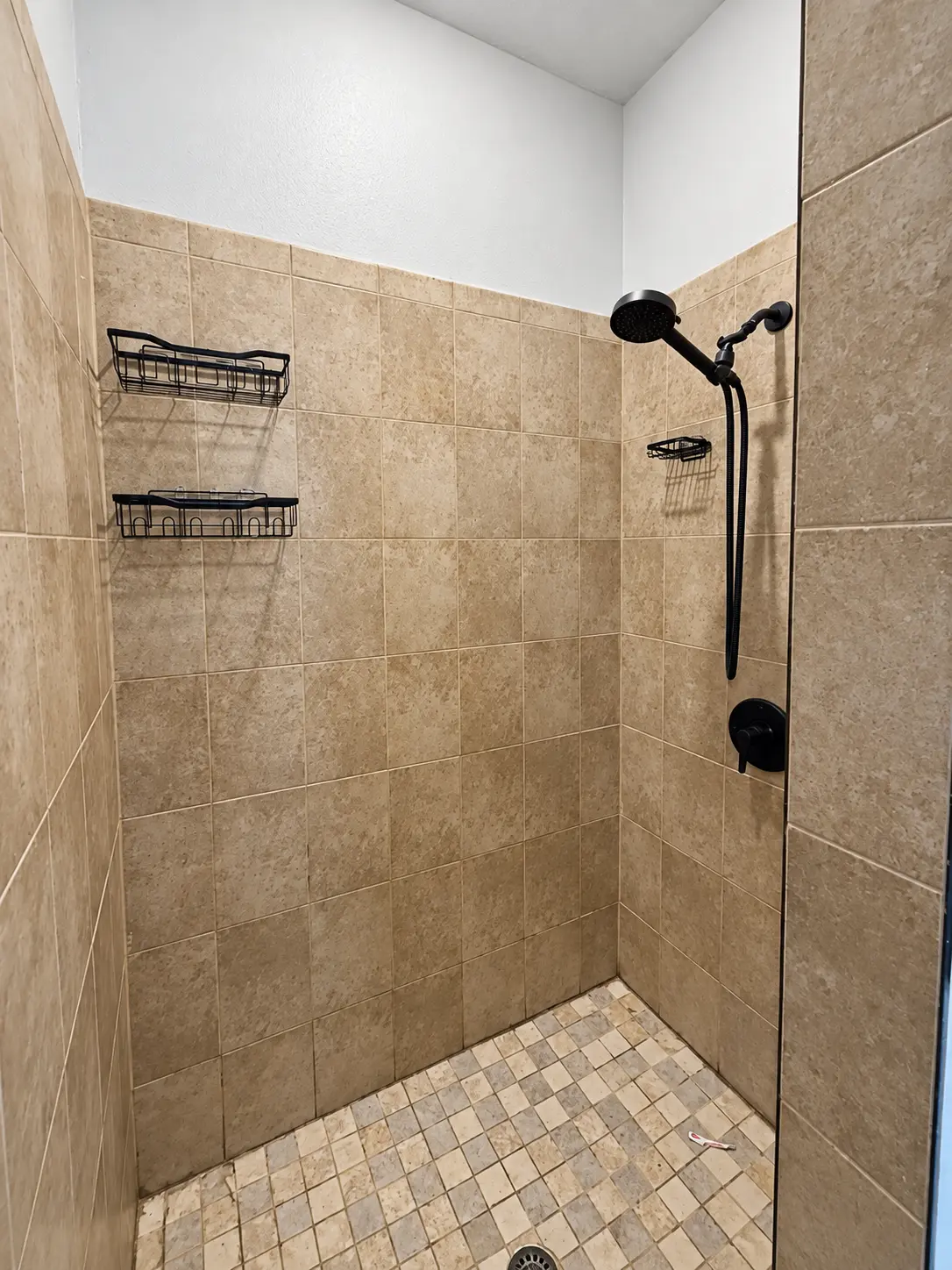 Beige tiled shower before a full bathroom renovation