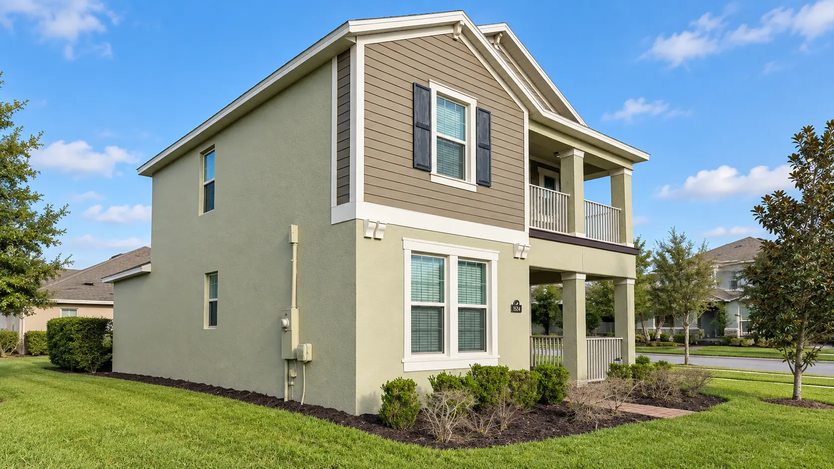 Side view of a repainted two-story home with sage stucco and tan siding